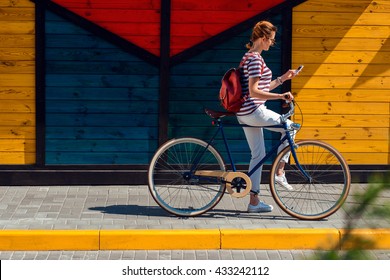 Young Woman With A Hire Bike Checking Her Phone, Space For Text