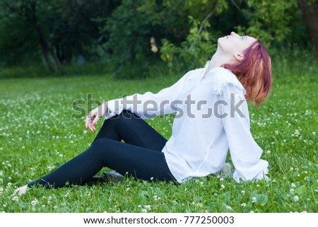 Young woman in historical costume dressed like a man sitting on the grass