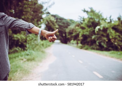 Young woman hitchhiking along a road.