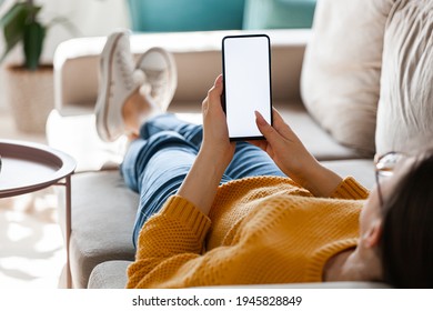 Young woman hold a mobile phone in hands, lying on the sofa