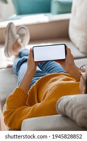 Young Woman Hold A Mobile Phone In Hands, Lying On The Sofa