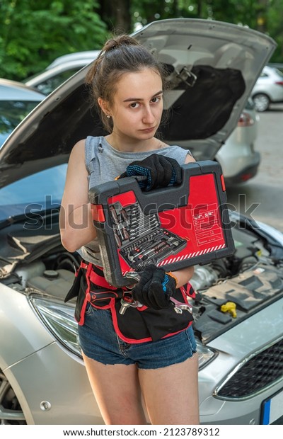 Young woman hold tools for repair and waiting\
for help near broken car. summer\
time