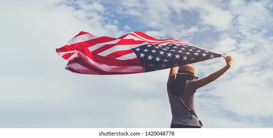 Young woman holding American flag on blue sky background with copy space.Vintage tone.Concept of America celebrate 4th of July.