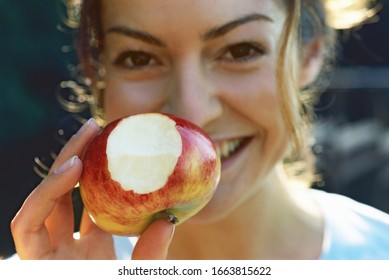 Young Woman Holding Apple With Bite Out Of It