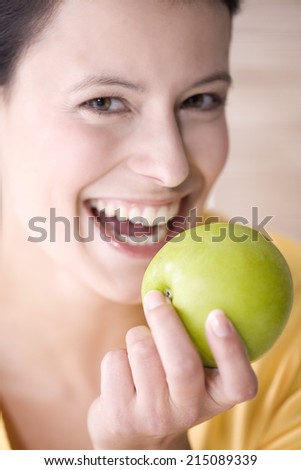 Young woman holding an apple, smiling, portrait