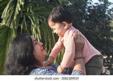 Young Woman Holding Up Baby Photo. Mom Holding Up Her Baby .