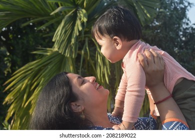 Young Woman Holding Up Baby Photo. Mom Holding Up Her Baby .