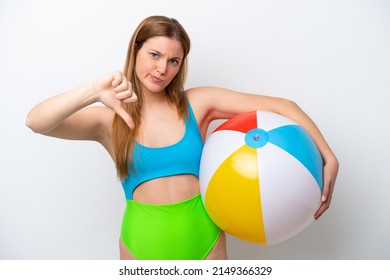 Young woman holding beach ball in holidays isolated on white background showing thumb down with negative expression