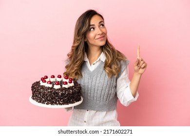 Young Woman Holding Birthday Cake Over Isolated Pink Background Pointing Up A Great Idea