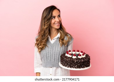 Young Woman Holding Birthday Cake Over Isolated Pink Background Thinking An Idea While Looking Up