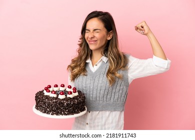 Young Woman Holding Birthday Cake Over Isolated Pink Background Doing Strong Gesture