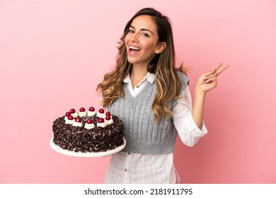 Young Woman Holding Birthday Cake Over Isolated Pink Background Smiling And Showing Victory Sign