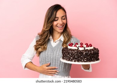 Young Woman Holding Birthday Cake Over Isolated Pink Background