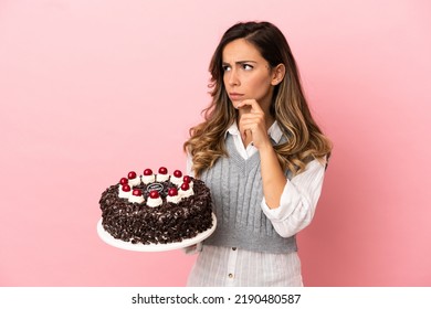 Young Woman Holding Birthday Cake Over Isolated Pink Background Having Doubts And Thinking