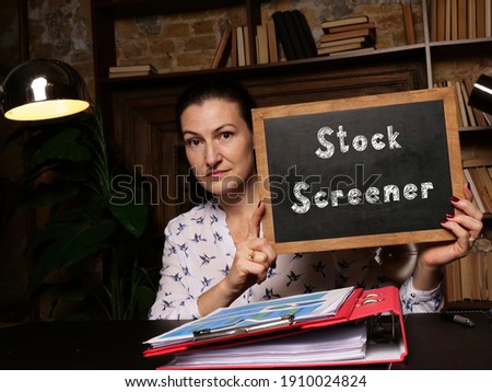 Young woman holding a black chalkboard in hands. Conceptual photo about Stock Screener with written text.
