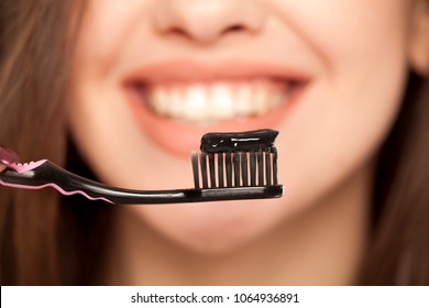 Young Woman Holding A Black Tooth Paste With Active Charcoal, And Black Tooth Brush On White Background