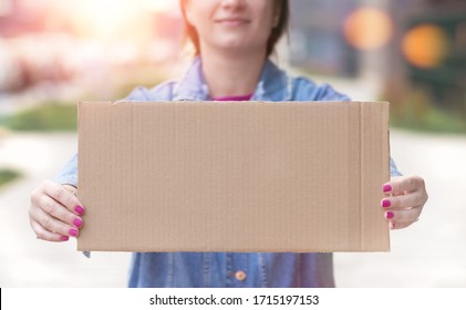 Young Woman Holding Blank Sign In Her Hands Close Up