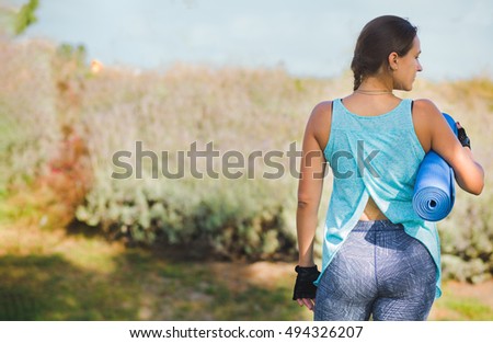 Young woman holding blue yoga mat, fitness.
