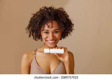 Young Woman Holding Bottle With Beauty Product In Studio