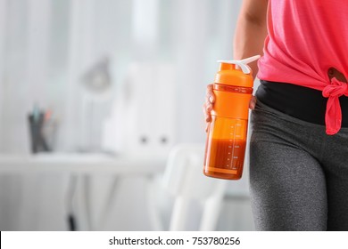 Young Woman Holding Bottle With Protein Shake Indoors