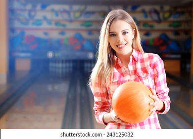 Young Woman Holding Bowling Ball In Club