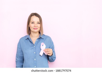 Young Woman Holding Brest Cancer Ribbon Over Pink Background.