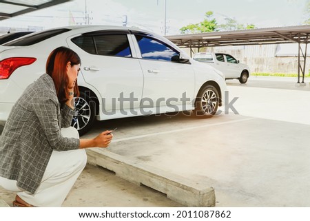 Young woman holding a car key sits dumbfounded at her own parking space that is empty as her car is stolen, while she runs errands : Car insurance theft in a shopping mall concept