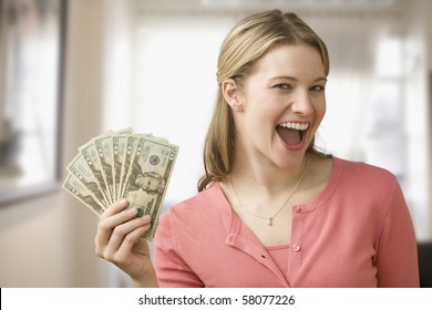 A Young Woman Is Holding Up Cash In A Fan And Smiling At The Camera.  Horizontal Shot.