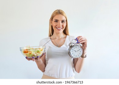 Young woman holding clock and Healthy food of salad Intermittent fasting concept. Time to lose weight , eating control or time to diet concept. - Shutterstock ID 1967366713