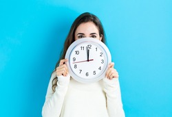Young Woman Holding A Clock Showing Nearly 12