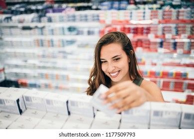 Young Woman Holding Cosmetics In Her Hand In Drugstore Department Of A Supermarket.