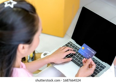 Young woman holding credit card and using laptop computer, Happy woman doing online shopping at home, Online shopping concept.