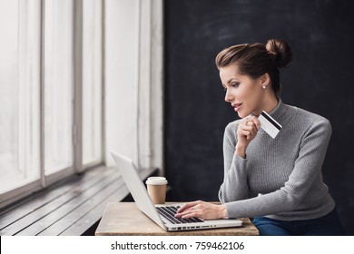 Young woman holding credit card and using laptop computer. Girl working online. Online shopping, e-commerce, internet banking, spending money, working from home concept