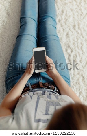 Young woman holding credit card and using phone sitting on floor. Payment.  Online shopping concept.Concept of blogging. Modern technologies Top view.