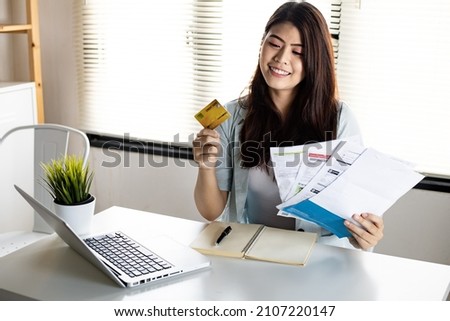 Young woman holding credit card and bill with smile happily after no debt. Not worried about the problems caused by credit card debt.