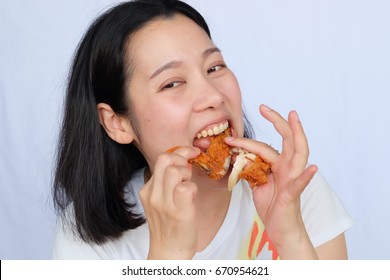 Young woman holding and eating fries chicken