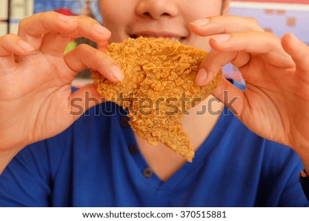 Young woman holding and eating fries chicken 