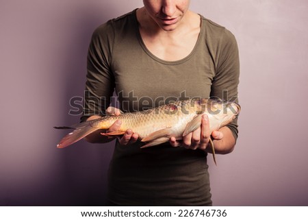 A young woman is holding and examining a carp