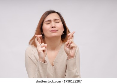 young woman holding fingers crossed for good luck on white background - Shutterstock ID 1938122287