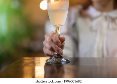 A young woman holding a glass of champagne in a warm atmosphere