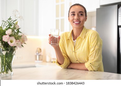 Young Woman Holding Glass Of Pure Water In Kitchen