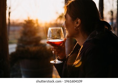 young woman holding a glass of red wine, outdoors, at sunset. - Powered by Shutterstock