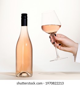 Young Woman Holding Glass Of Rose Wine On White Background. Hand With Black Polish.