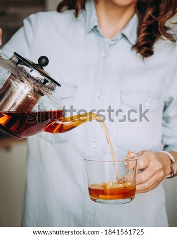 Young woman holding a glass teapot. Woman pouring tea