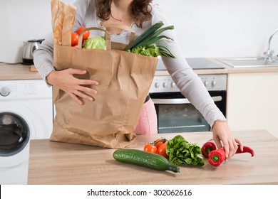 Young Woman Holding Grocery Bag With Vegetables At Home