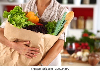 Young Woman Holding Grocery Shopping Bag With Vegetables Standing In The Kitchen