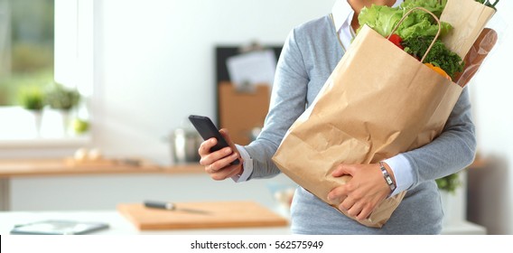 Young Woman Holding Grocery Shopping Bag With Vegetables . Standing In The Kitchen