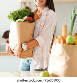 Young woman holding grocery shopping bag with vegetables - Shutterstock ID 716835958