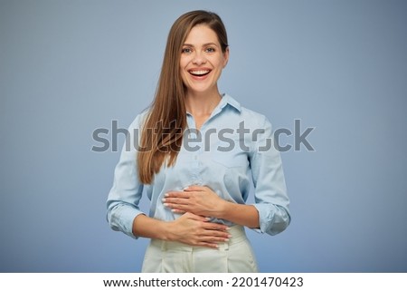 Young woman holding hands on stomach. isolated portrait. Happy girl on blue background.