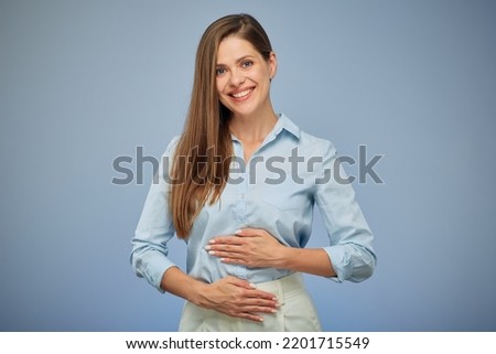Young woman holding hands on stomach. isolated portrait. Happy girl on blue background.